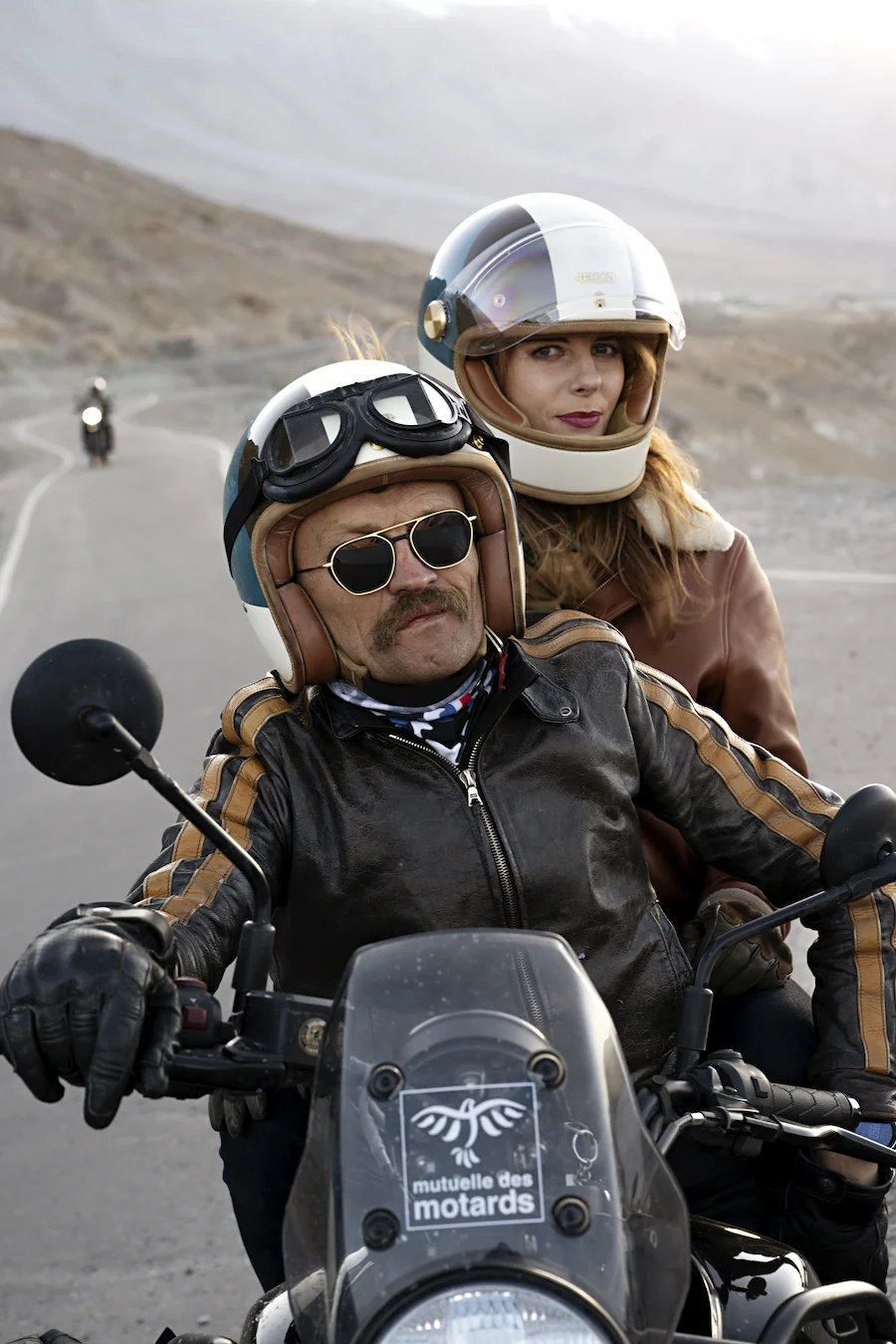 Mann mit Brett Eyewear Sonnenbrille auf Motorrad, begleitet von Frau mit Helm – markanter Stil und Vintage-Charakter