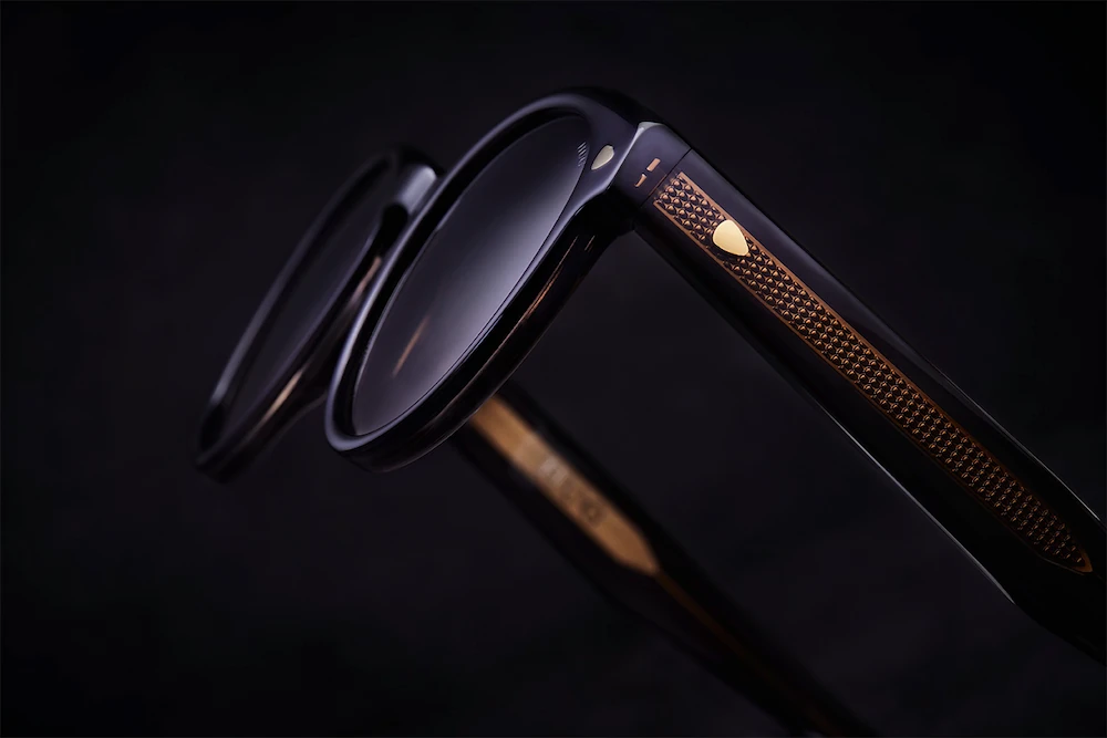 Detailaufnahme einer dunklen HUG Brillenfassung mit warm schimmerndem Bügeldetail